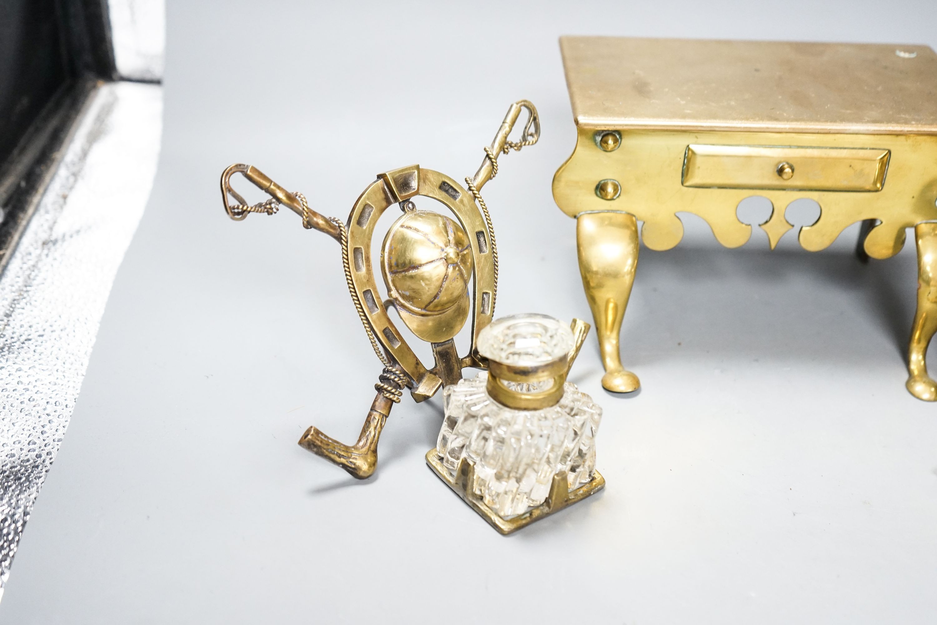 A brass Jockey-related inkwell, a miniature brass footman and brass hand bells